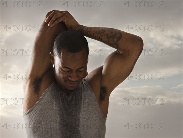 Young man exercising, cloudy sky in background. Photo : Mike Kemp