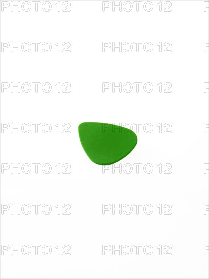 Green plectrum on white background. Photo : David Arky