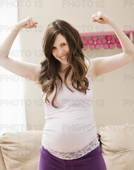 Young pregnant woman flexing muscles. Photo : Mike Kemp