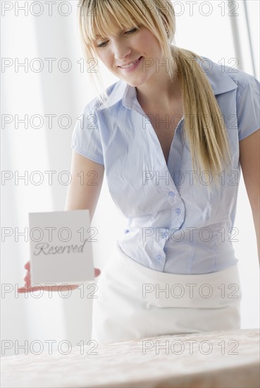 Waitress placing reserved sign on table. Photo : Jamie Grill Photography