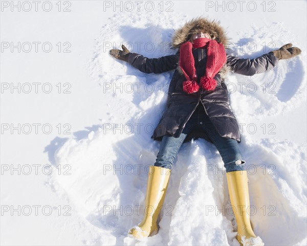 Young woman doing snow angel. Photo : Jamie Grill Photography