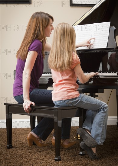 Girl (8-9) and mother playing grand piano. Photo : Mike Kemp