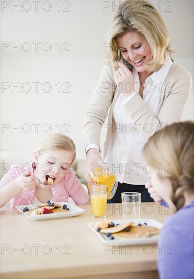 Mother and daughters (8-11) eating breakfast. Photo : Jamie Grill Photography