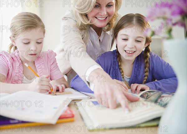 Mother helping daughters (8-11) with homework. Photo : Jamie Grill Photography
