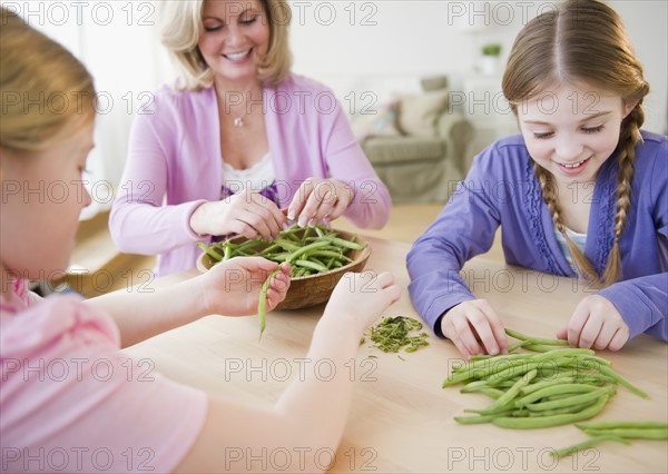 Mother and daughters (8-11) husking vegetables. Photo : Jamie Grill Photography