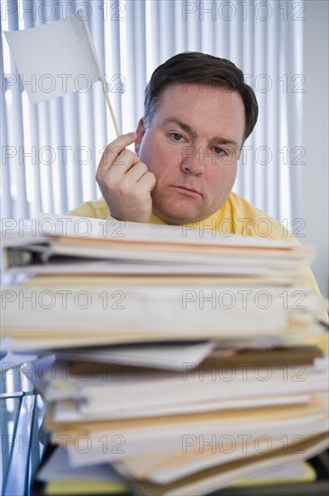 Businessman holding white flag over stack of paperwork. Photo: Jamie Grill Photography