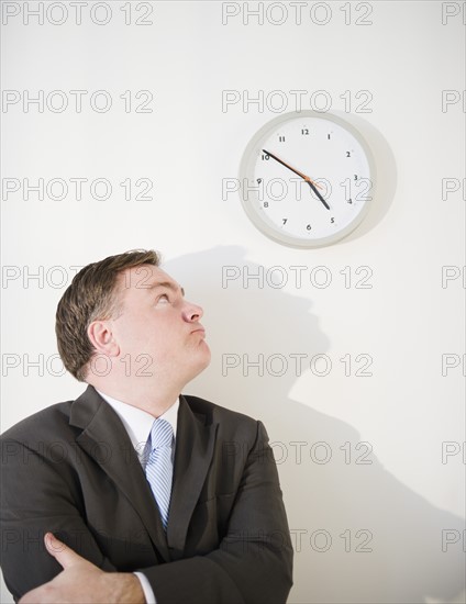 Businessman looking up at clock. Photo: Jamie Grill Photography