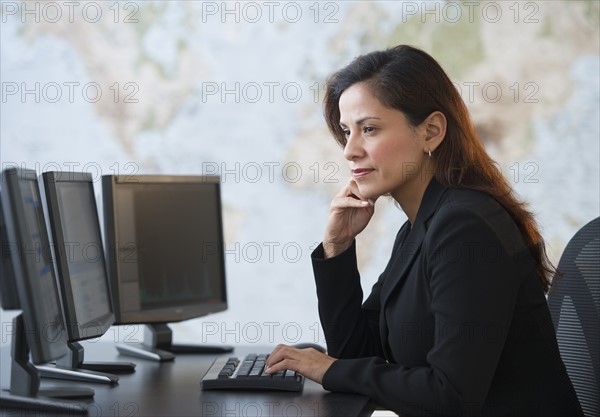 Woman working at desk with monitors.