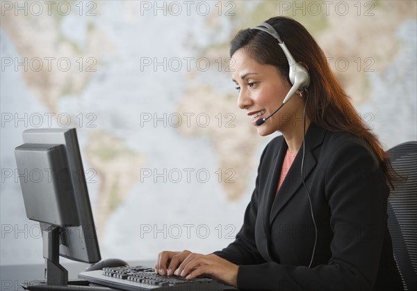 Female customer service representative with headset working on computer.