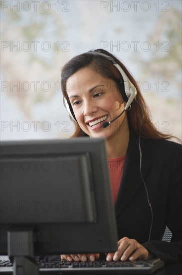 Female customer service representative with headset working on computer.