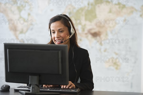 Female customer service representative with headset working on computer.