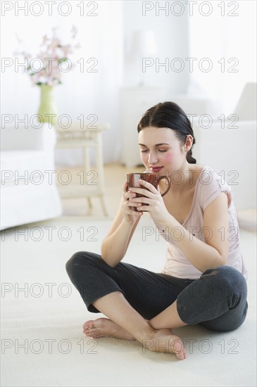 Woman sitting on floor and drinking. Photo : Daniel Grill