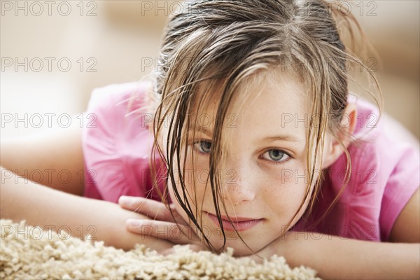 Portrait of girl (10-11) lying on floor. Photo : Mike Kemp