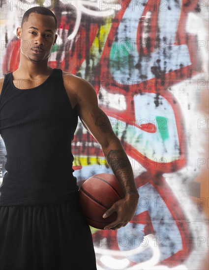 USA, Utah, Salt Lake City, portrait of basketball player in front of graffiti. Photo : Mike Kemp