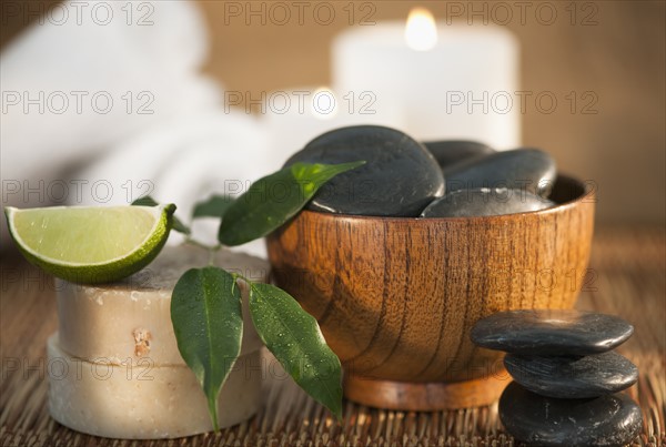 Hot stones and slice of lime, candle in background.