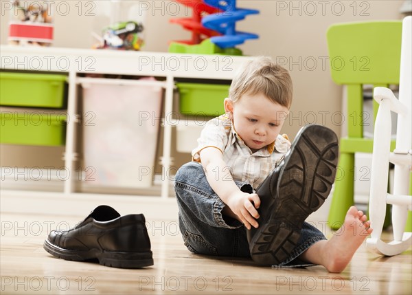 Boy (2-3) putting on dad's shoes. Photo : Mike Kemp
