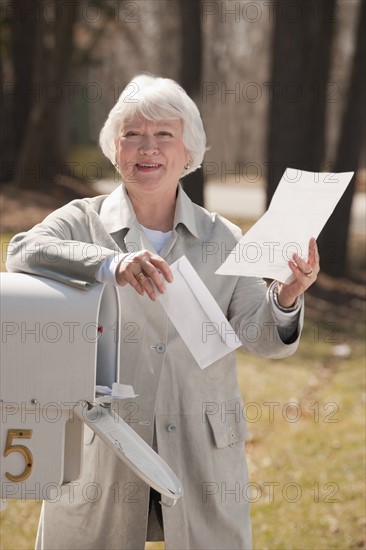 USA, Virginia, Richmond, senior woman reading letters by mailbox. Photo : Mark Edward Atkinson