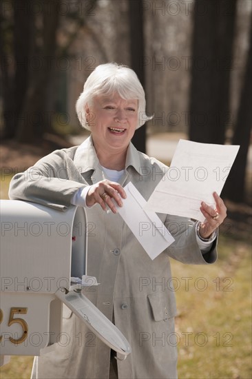 USA, Virginia, Richmond, senior woman reading letters by mailbox. Photo: Mark Edward Atkinson