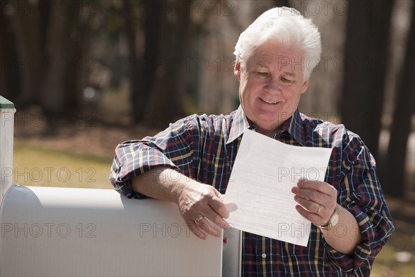 USA, Virginia, Richmond, senior man reading letter by mailbox. Photo : Mark Edward Atkinson