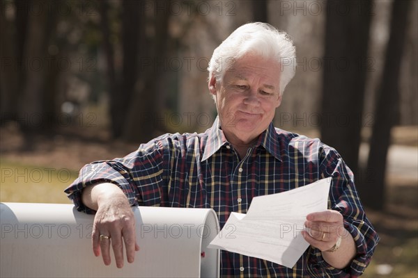 USA, Virginia, Richmond, senior man reading letter by mailbox. Photo : Mark Edward Atkinson