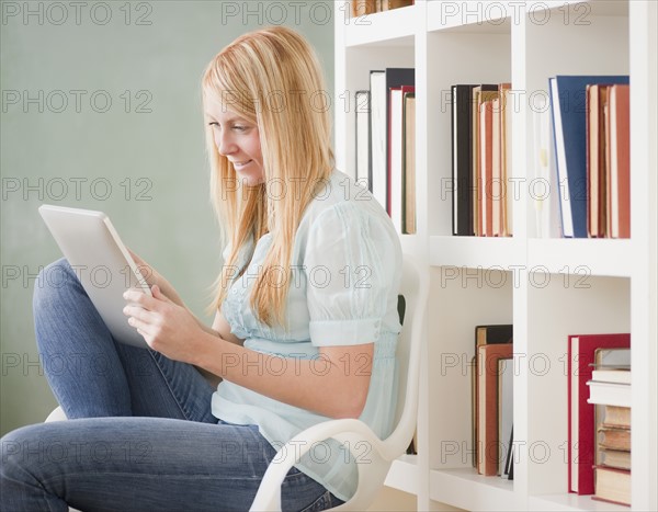 Female student in library using digital tablet. Photo : Jamie Grill Photography