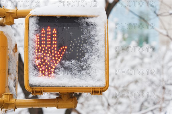 USA, New York City, New York, don't walk sign with hand covered with snow.
