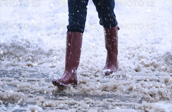 USA, New York, New York City, close up of woman's legs walking in winter slush.