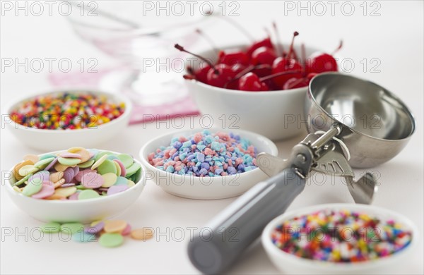 Close up of scoop and bowls with colorful toppings for ice creams.