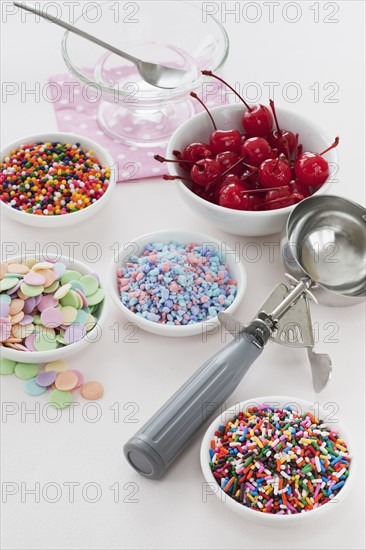 Close up of scoop and bowls with colorful toppings for ice creams.