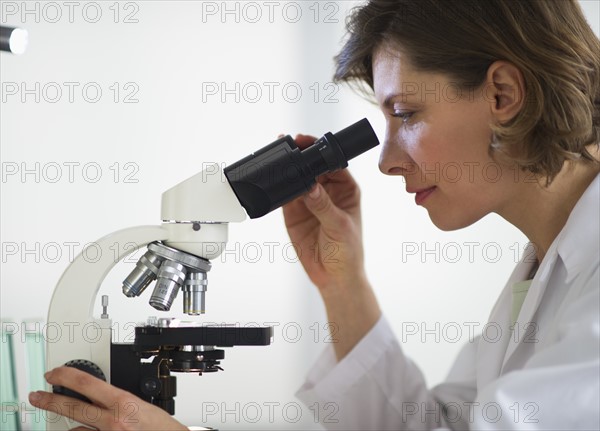 Woman in laboratory looking through microscope.