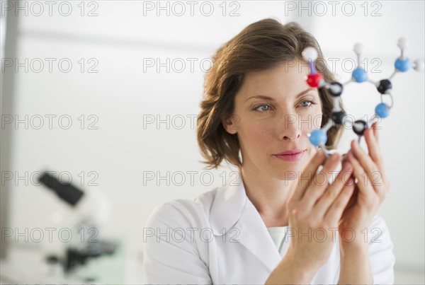 Woman in laboratory holding molecule model.