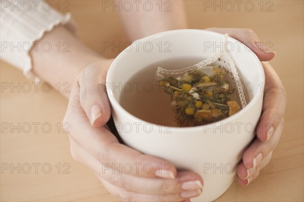 Woman holding cup with chamomile tea.