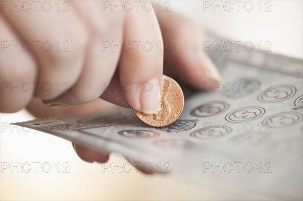 Studio shot of woman scratching lottery ticket.