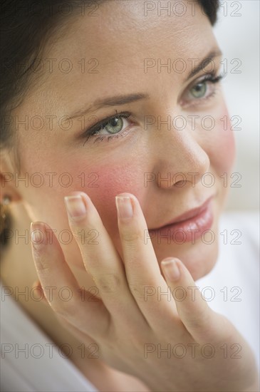 Woman applying cosmetics on face.