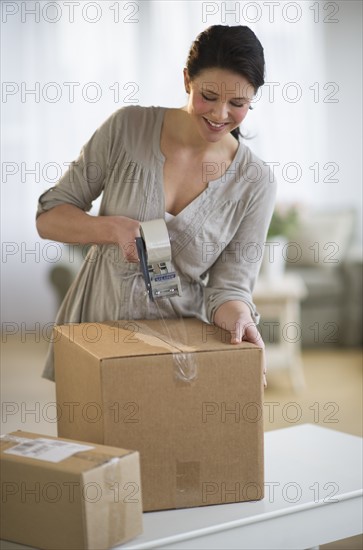 Woman taping cardboard boxes.