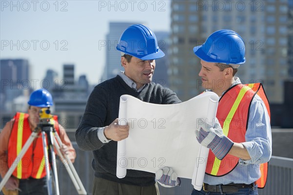 USA, New Jersey, Jersey City, construction workers reading blueprint.