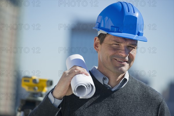 Portrait of construction worker holding rolled up blueprint.