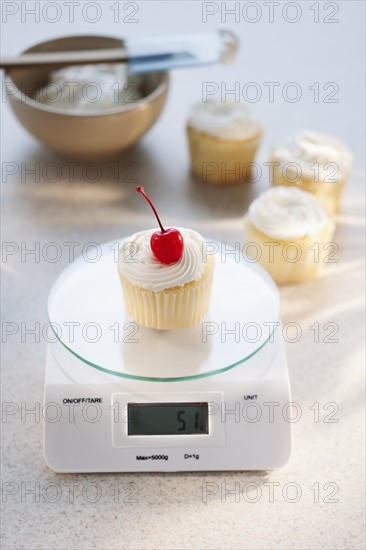 Studio shot of cupcake on weight scale.