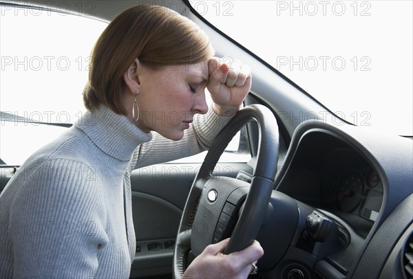 Woman driving car looking upset.