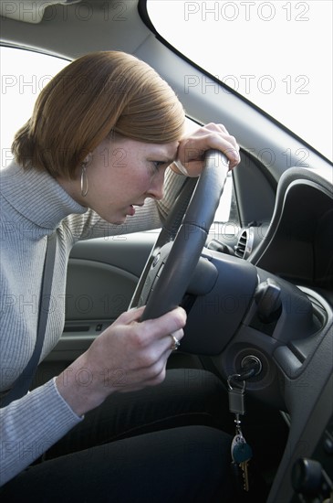 Woman driving car looking upset.