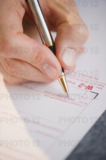 Hand filling tax form. Photo : Jamie Grill Photography