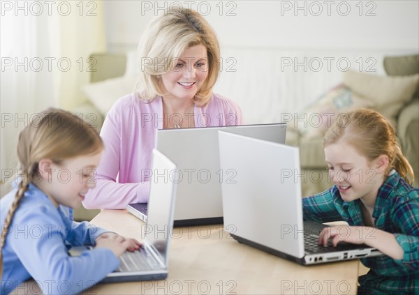 Mother and daughters (8-11) using laptop. Photo : Jamie Grill Photography