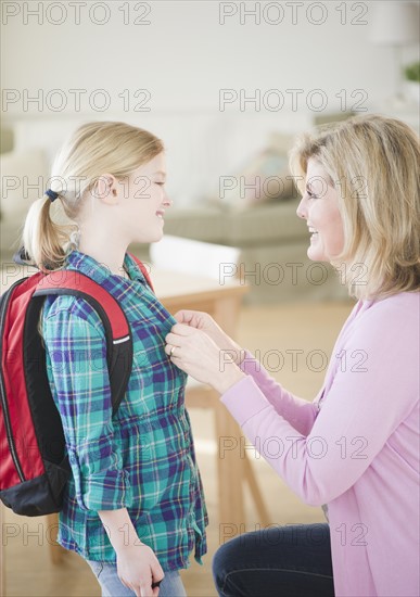 Mother buttoning daughter's (8-9) shirt. Photo : Jamie Grill Photography