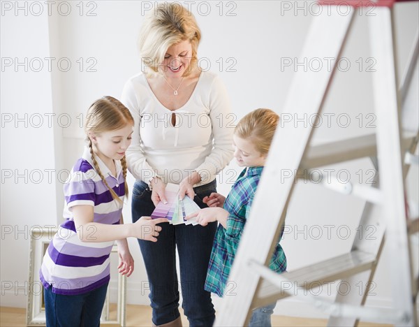 Mother and daughters (8-11) choosing color swatches. Photo : Jamie Grill Photography