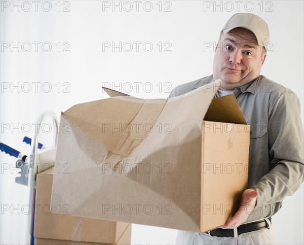 Delivery man holding damaged box. Photo : Jamie Grill Photography