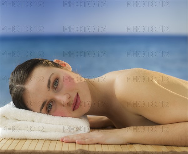 Woman lying on massage table with ocean behind. Photo : Daniel Grill