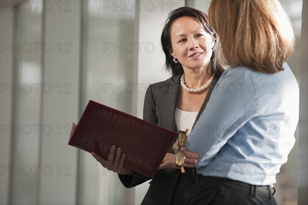 Businesswomen talking in corridor. Photo : Mark Edward Atkinson