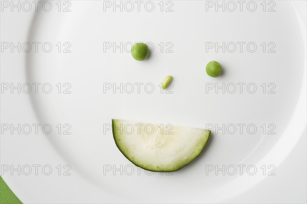Anthropomorphic face made up from green peas and cucumber slice. Photo : Kristin Lee