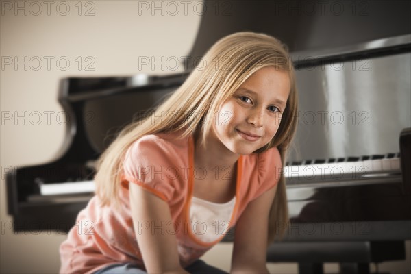 Portrait of girl (8-9) sitting by piano. Photo: Mike Kemp