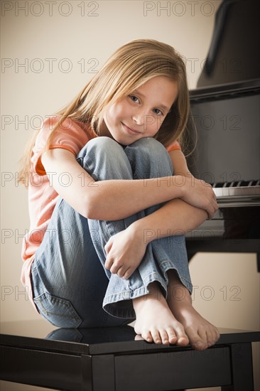 Portrait of girl (8-9) sitting by piano. Photo: Mike Kemp